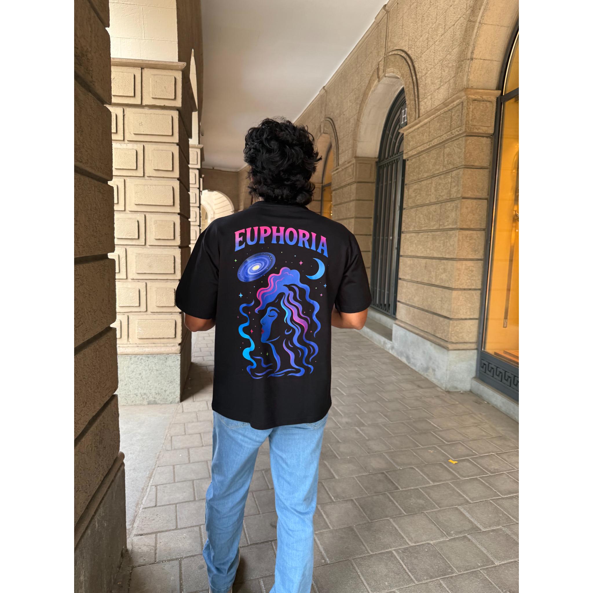 Person wearing a black t-shirt with 'Euphoria' design walking in an architectural setting.